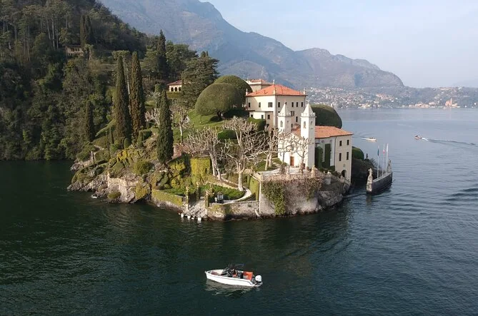 Kleines Boot auf dem Comer See vor einer Villa am Ufer